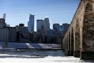 The Minneapolis skyline provides a picturesque backdrop for the historic Stone Arch Bridge and Mississippi River shoreline.