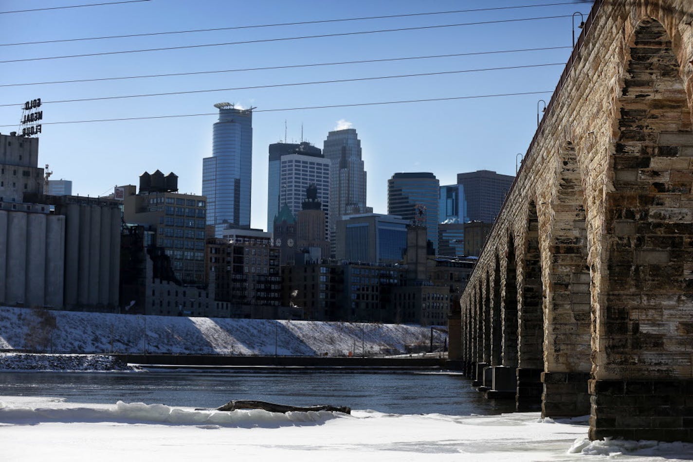 The Minneapolis skyline provides a picturesque backdrop for the historic Stone Arch Bridge and Mississippi River shoreline.