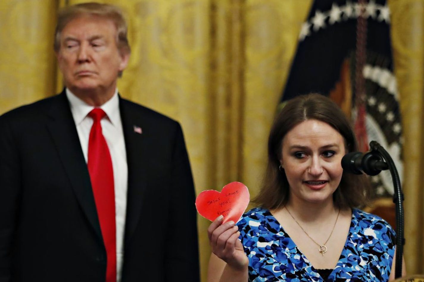 Polly Olson holds up a heart that says "Jesus Loves You" during an event with President Donald Trump to sign an executive order requiring colleges to certify that their policies support free speech as a condition of receiving federal research grants, Thursday March 21, 2019, in the East Room of the White House in Washington. Olson said that while attending Northeast Wisconsin Technical College the college had limited her from handing out Valentine's Day cards with religious messaging on campus.