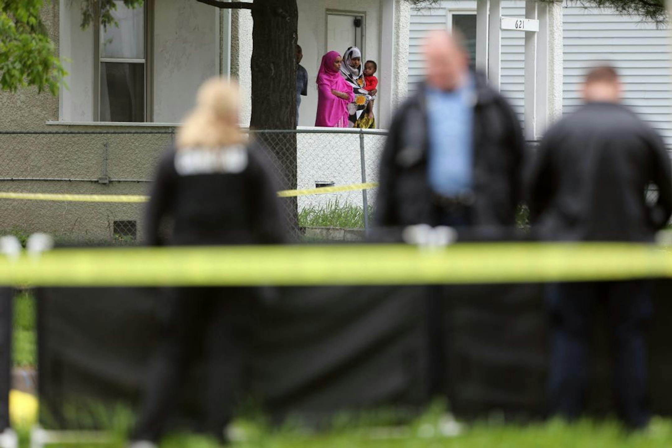 A family watched from there porch as investigators photographed a body at Olson Memorial High where a person was shot in killed Wednesday 11, 2016 in the 700 block of Oliver Avenue North Minneapolis, MN.