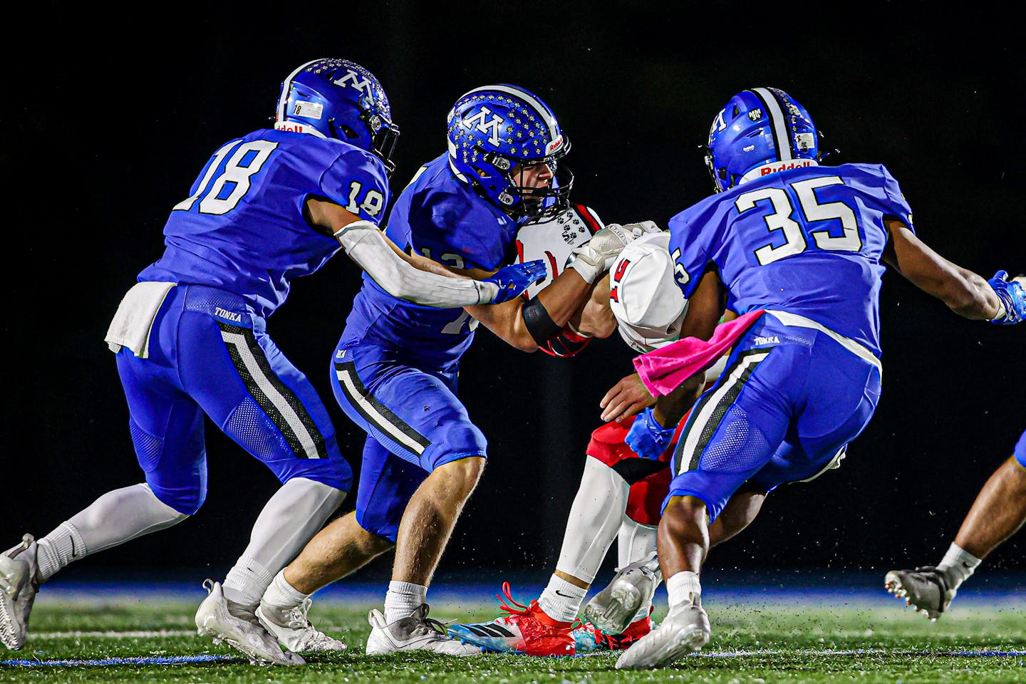 Minnetonka defender Ashton Hoffman (13) and teammates Casey Miller (8) and Prentice Wheatley (35) take down Centennial quarterback Daylen Cummings (12) on a fourth-down play in the third quarter of the Skippers' 31-7 victory. Centennial at Minnetonka, 10-15-21. Photo by Mark Hvidsten, SportsEngine