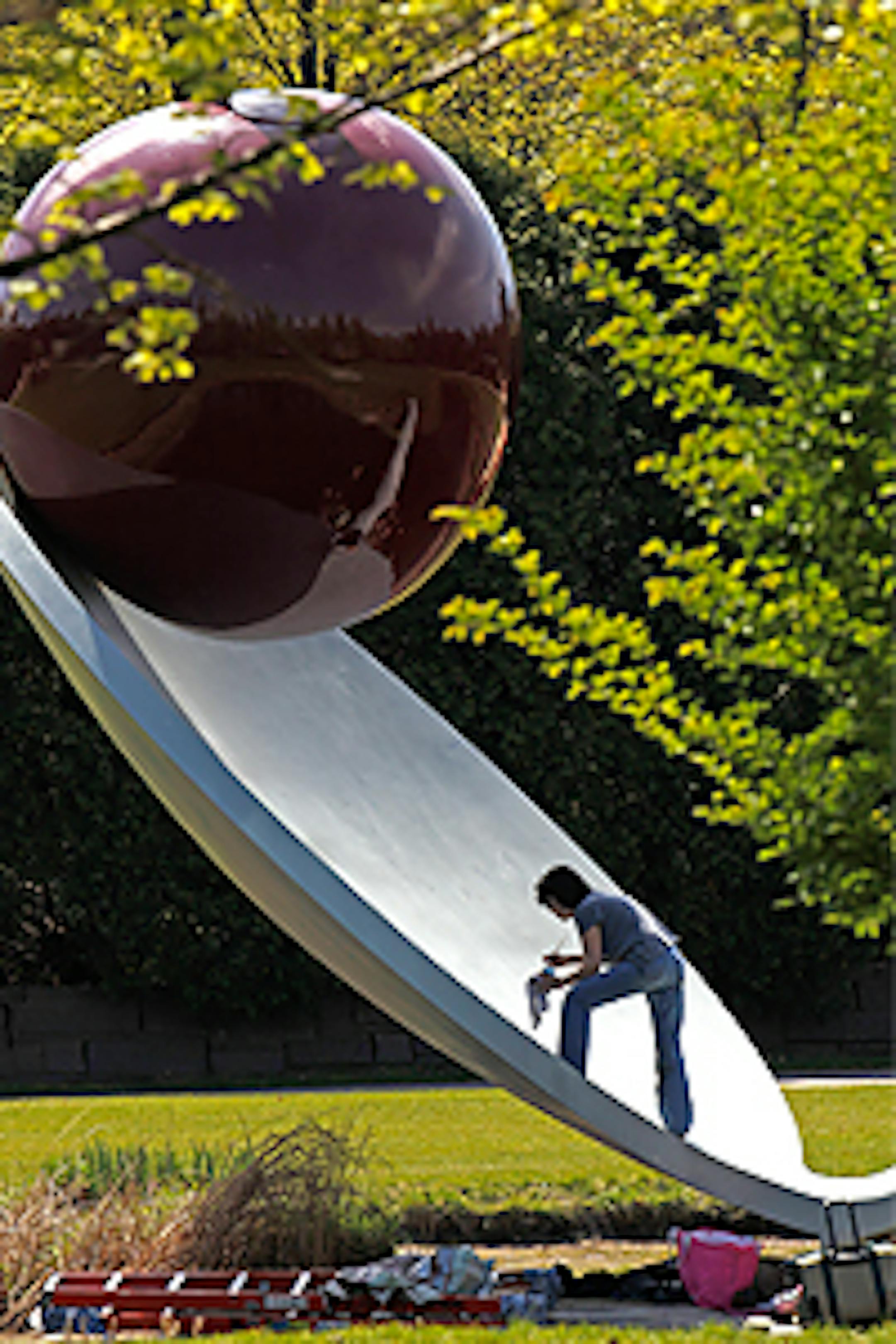 Donna Haberman removes graffiti from the "Cherry Spoon" in the Walker sculpture garden.