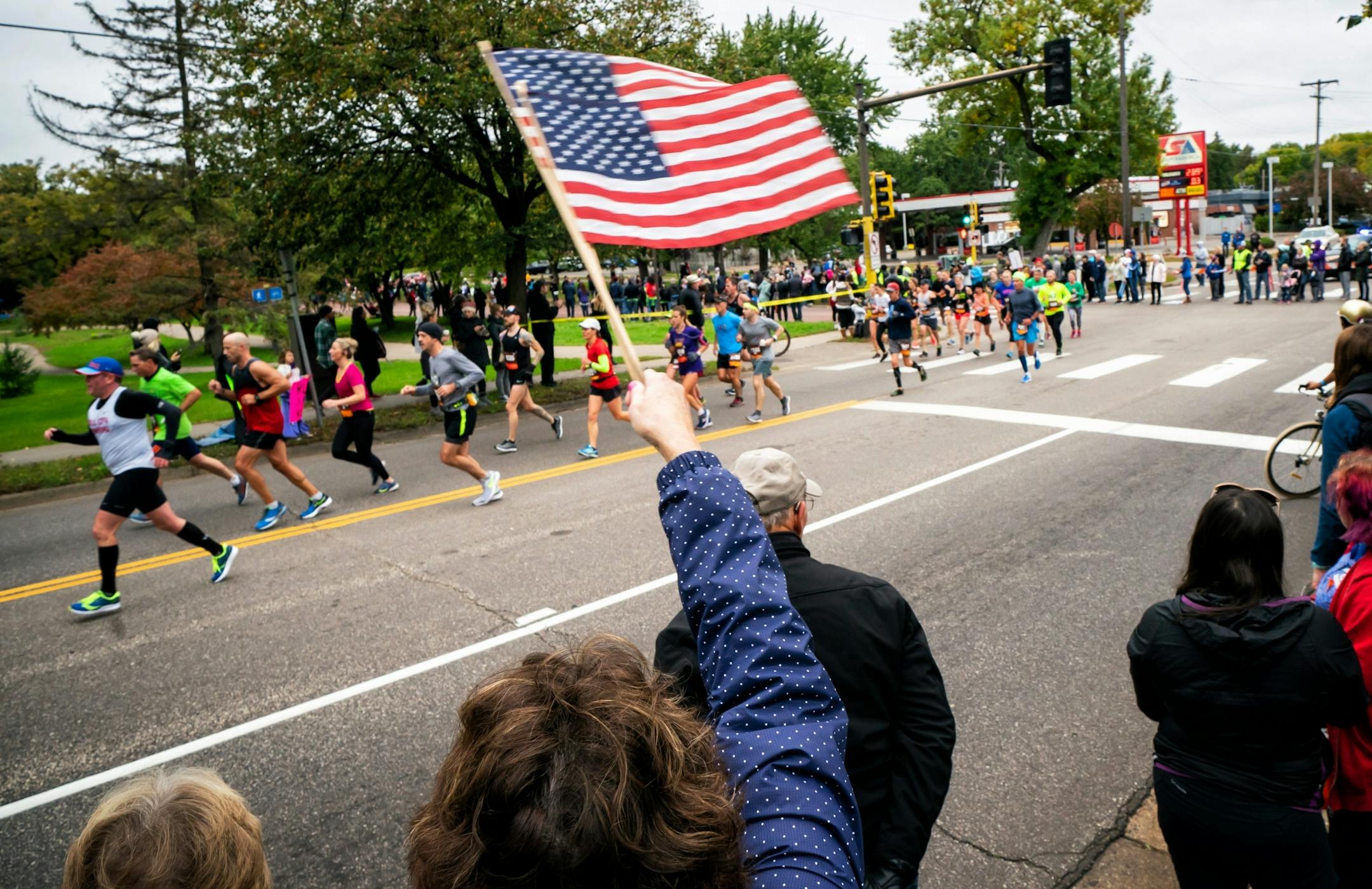 Kris McCormack waved flags to get the attention of her son in law along Cedar Ave during the Twin Cities Marathon.