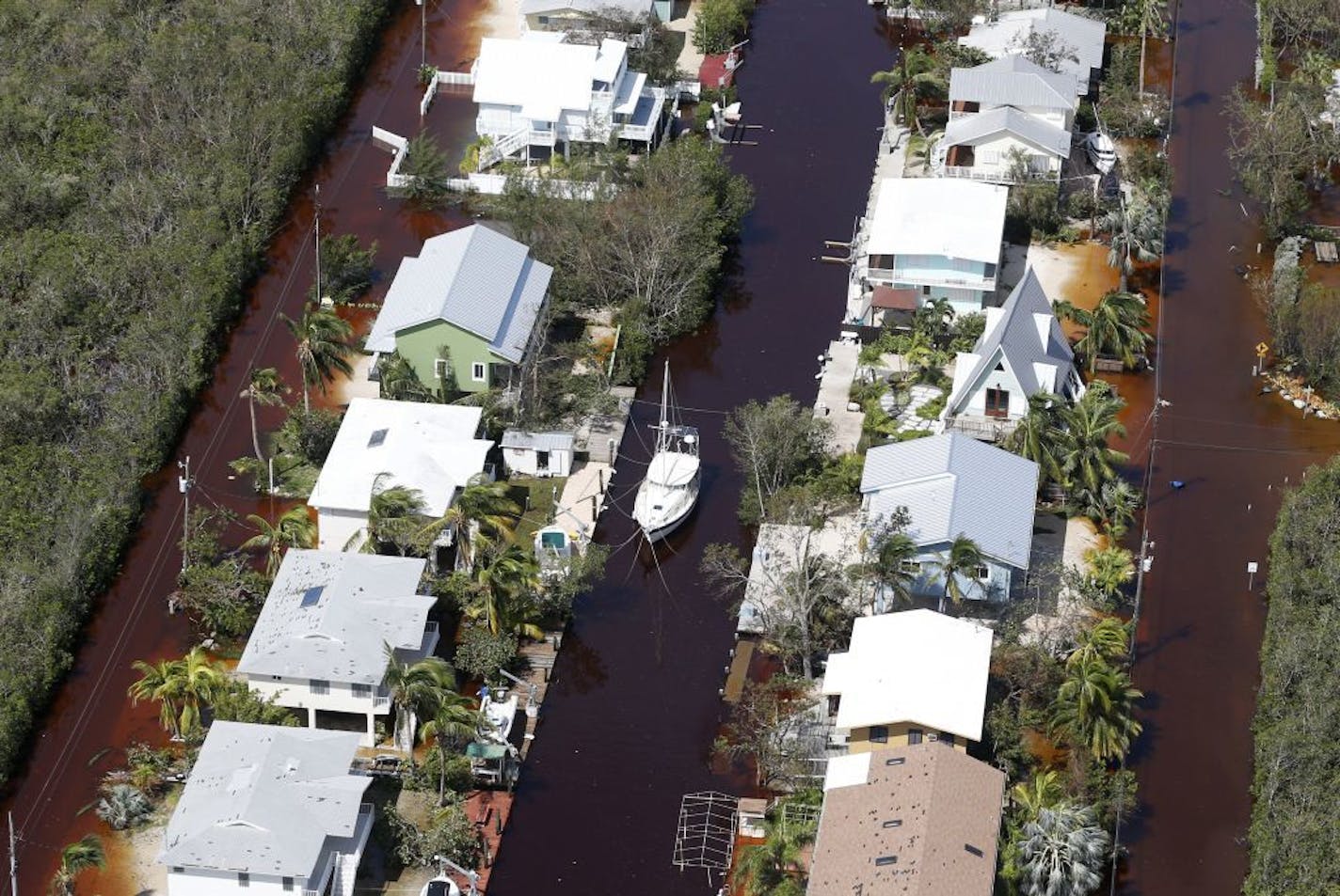 A boat lies secured in a canal between homes and flooded streets in the aftermath of Hurricane Irma, Monday, Sept. 11, 2017, in Key Largo, Fla.