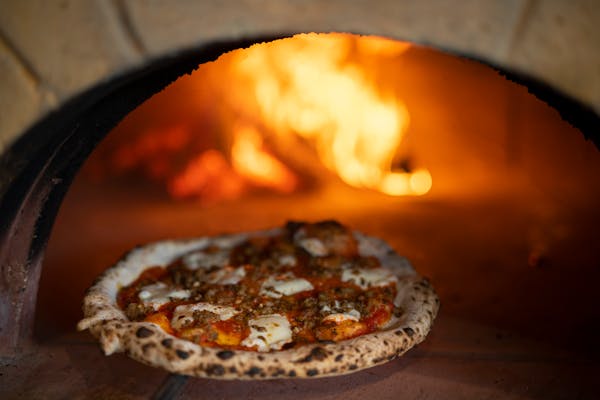 What's becoming a signature feature of Daniel del Prado's restaurant's - a wood fired pizza oven - is the centerpiece of a seating area off the bar an