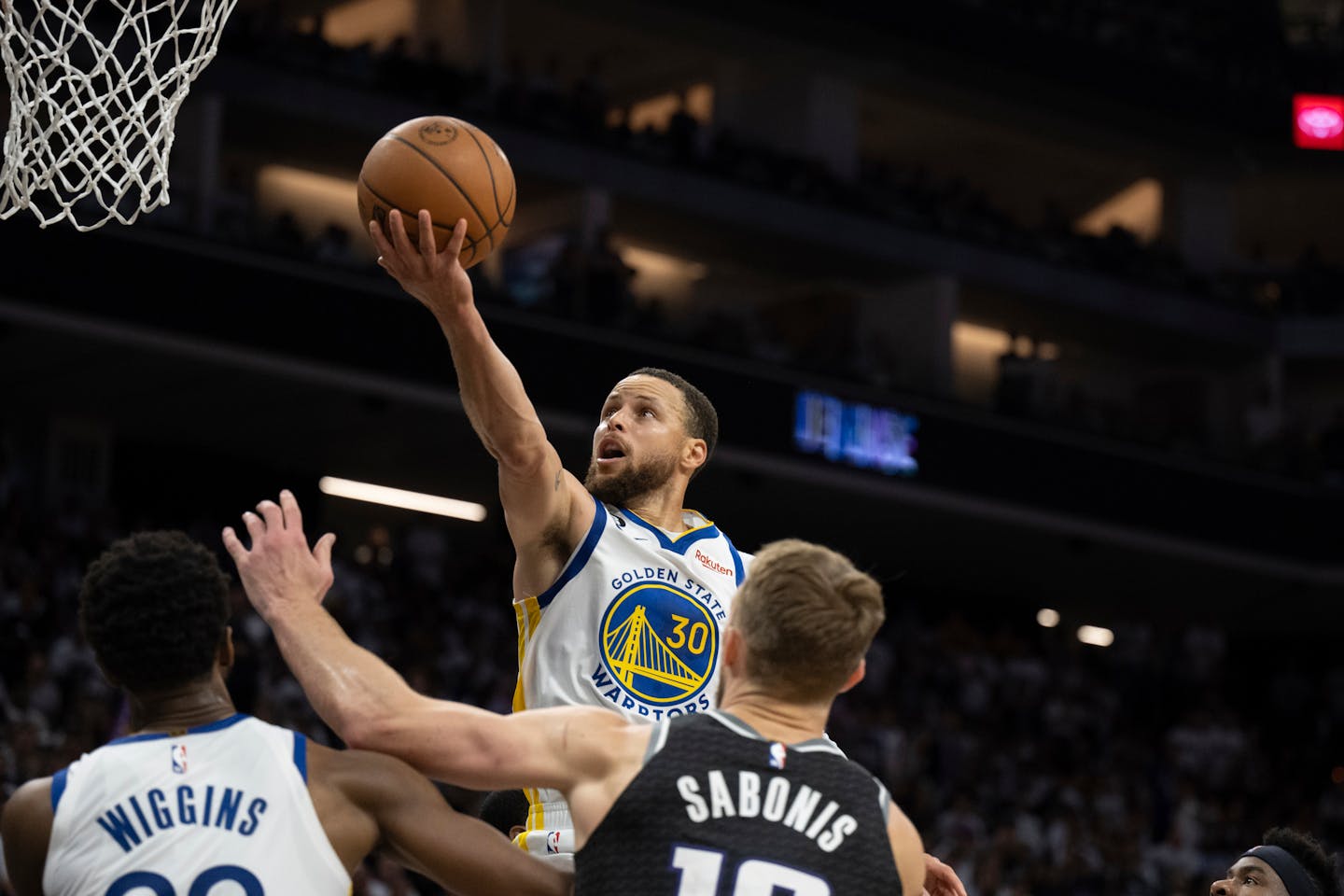 Golden State Warriors guard Stephen Curry (30) scores between Warriors forward Andrew Wiggins, left, and Sacramento Kings forward Domantas Sabonis, third from left, during the second half of Game 7 of an NBA basketball first-round playoff series Sunday, April 30, 2023, in Sacramento, Calif. (AP Photo/José Luis Villegas)