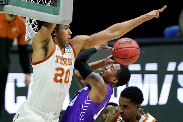 Texas’ Jericho Sims (20) blocked the path of Abilene Christian’s Mahki Morris during an NCAA tournament game March 20 in Indianapolis. 