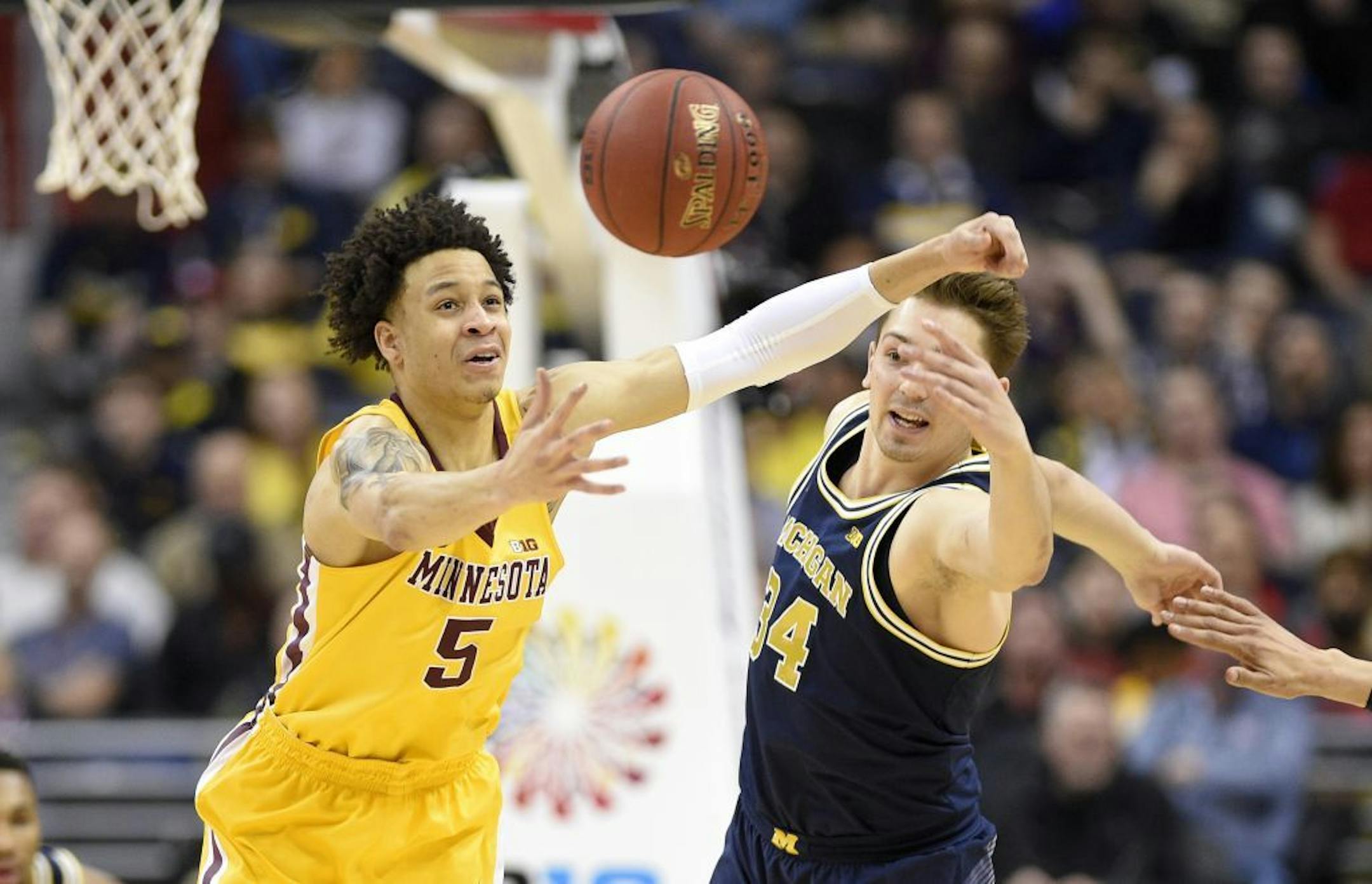 Minnesota guard Amir Coffey (5) fights for the ball with Michigan forward Mark Donnal (34) during the first half of an NCAA college basketball game in the Big Ten tournament, Saturday, March 11, 2017, in Washington.