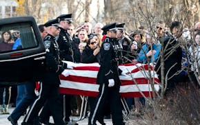 The Burnsville Police Honor Guard carried the casket of one of two fallen officers in front of family outside Ballad-Sunder Funeral and Cremation in J