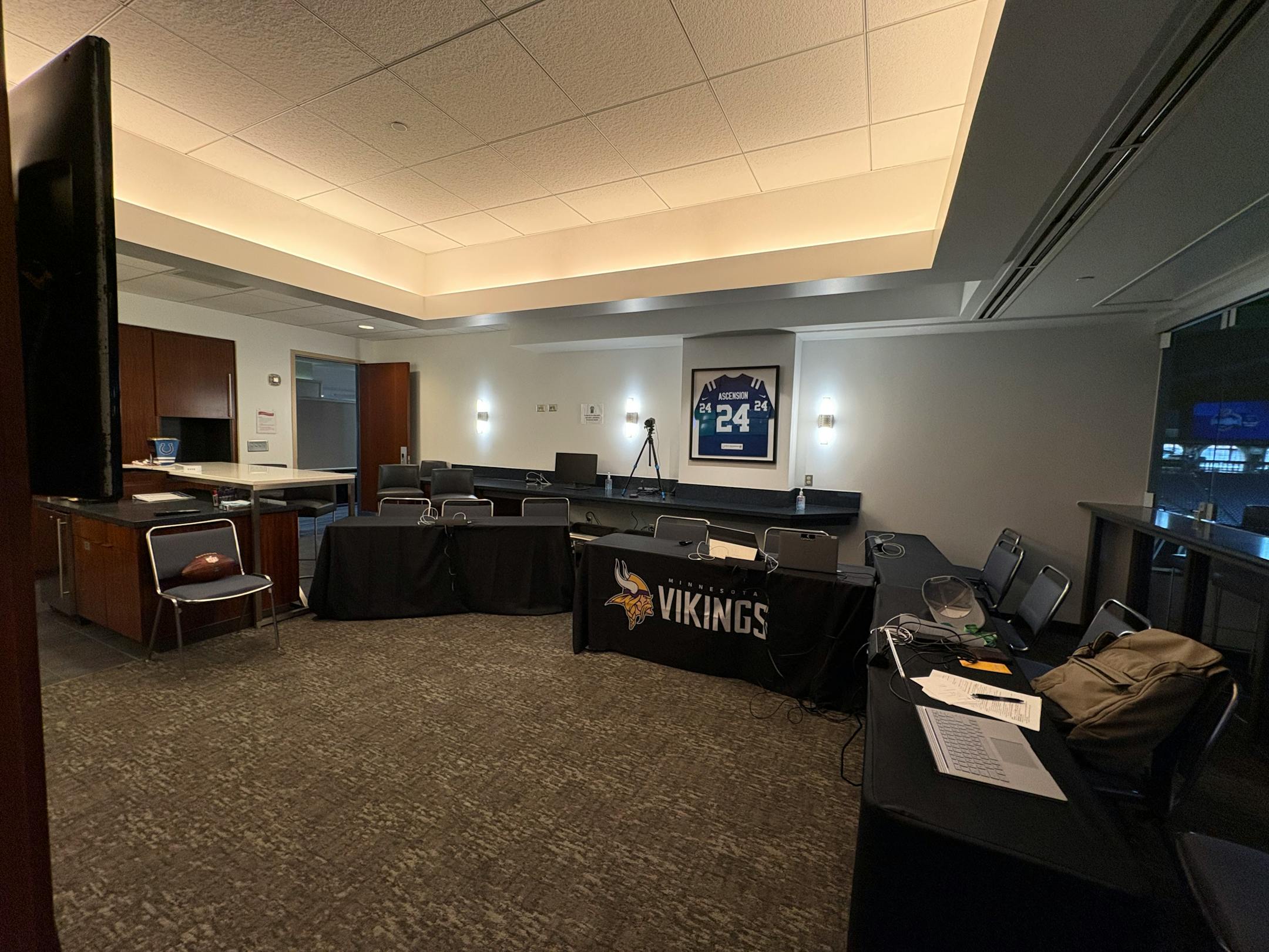 A horizontal photo of a suite inside Lucas Oil Stadium which the Vikings have converted to their formal interview room for the NFL Combine. There are four tables set up and arranged in a partial U-shape, with two-to-three chairs at each. A lone chair sits in the right of frame for the prospect to sit in.
