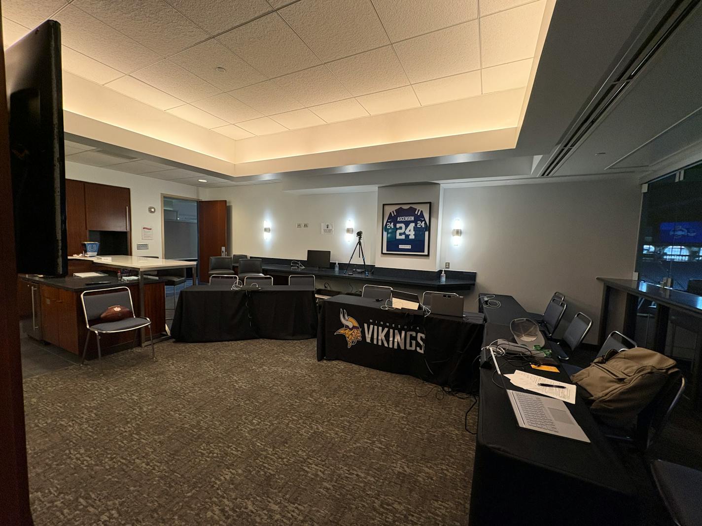 A horizontal photo of a suite inside Lucas Oil Stadium which the Vikings have converted to their formal interview room for the NFL Combine. There are four tables set up and arranged in a partial U-shape, with two-to-three chairs at each. A lone chair sits in the right of frame for the prospect to sit in.