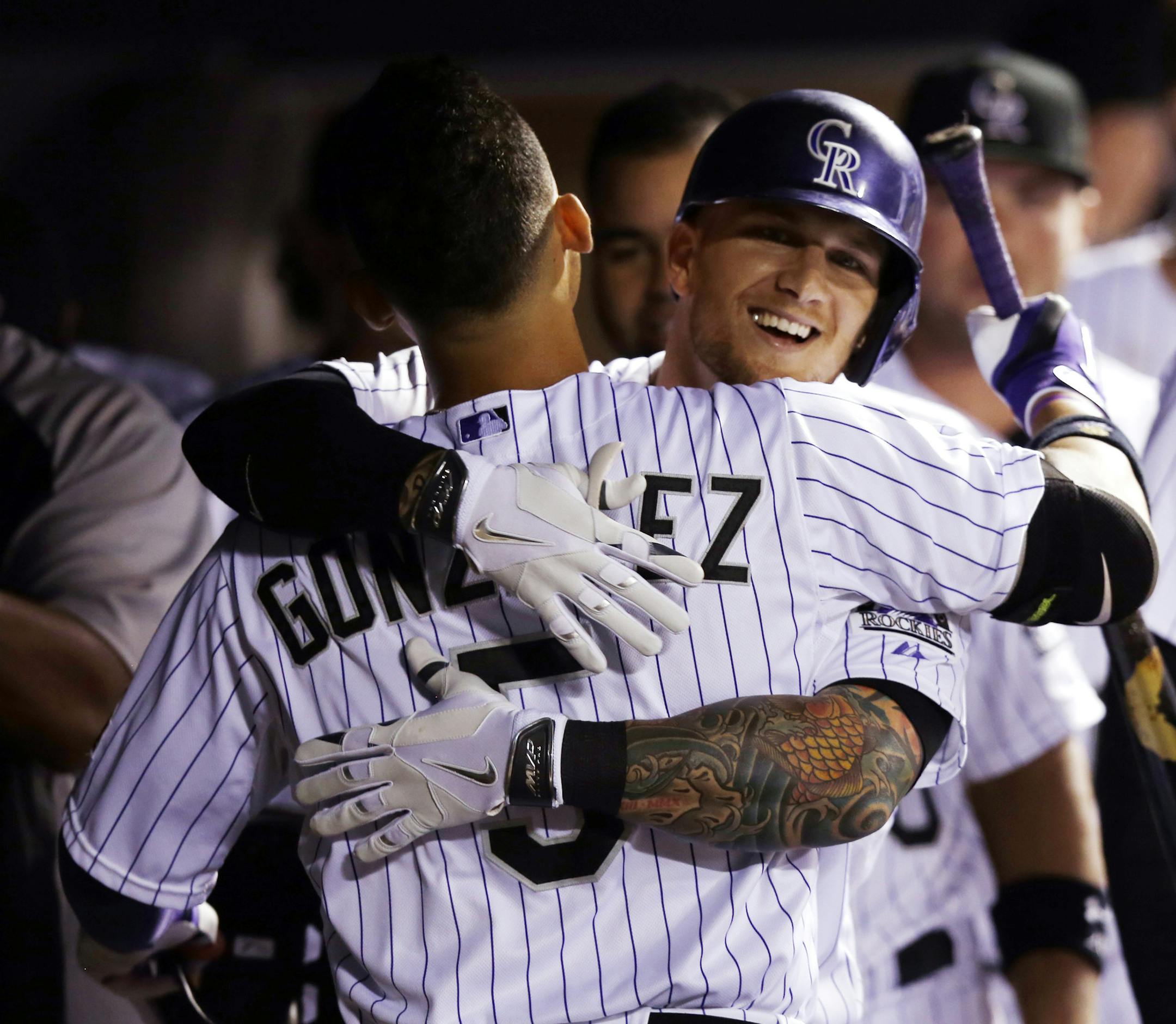 Colorado Rockies' Brandon Barnes hugs teammate Carlos Gonzalez (5) after hitting a solo home run against the Minnesota Twins during the seventh inning of a baseball game on Friday, July 11, 2014, in Denver. (AP Photo/Jack Dempsey)