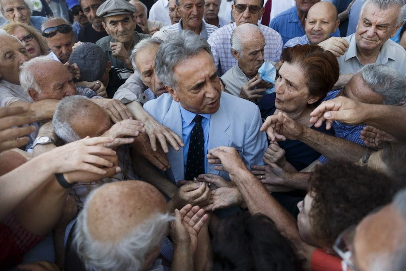 Pensioners try to get a number to enter a bank to get part of their pensions in Athens, Wednesday, July 1, 2015. About 1,000 bank branches around the country were ordered by the government to reopen Wednesday to help desperate pensioners without ATM cards cash up to 120 euros ($134) from their retirement checks. Eurozone finance ministers were set to weigh Greece's latest proposal for aid Wednesday.