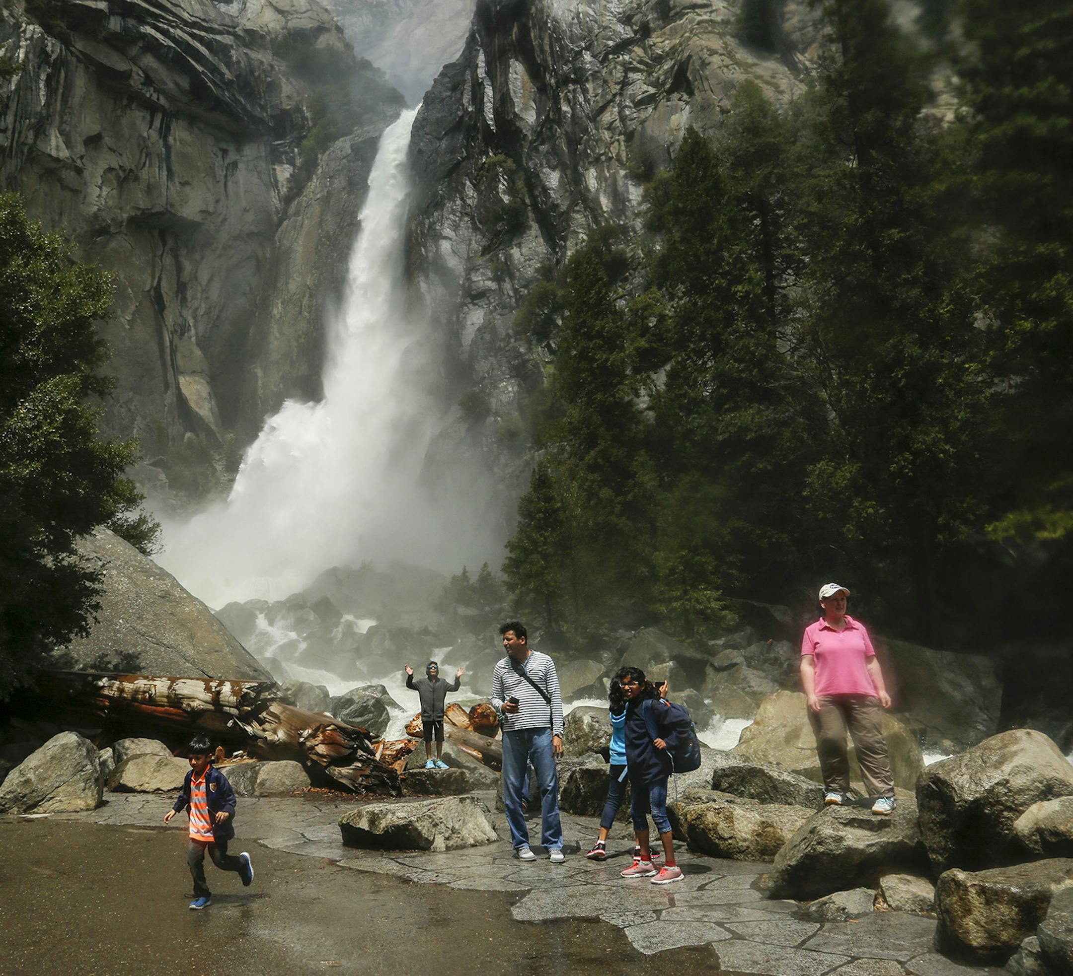 Visitors stand in a mist cloud while they snap pictures of the gushing Lower Yosemite Fall in the Yosemite Valley May 5, 2017. (Mark Boster/Los Angeles Times/TNS)