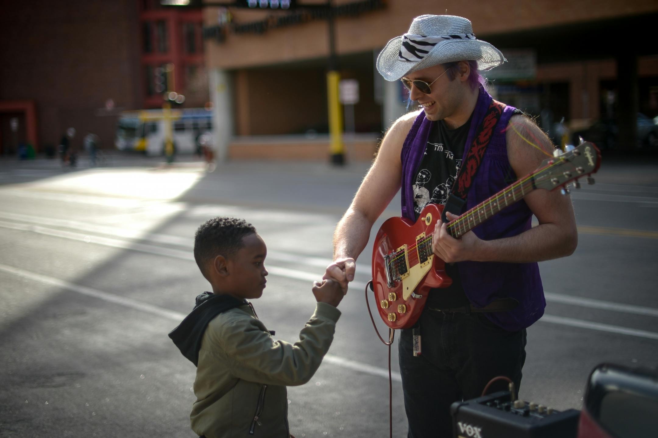 Trevor Charnley, of Minneapolis, bumped fists with Emarion Crossley, 6, of Chicago, after letting Crossley play a few notes on his guitar Friday outside First Avenue.