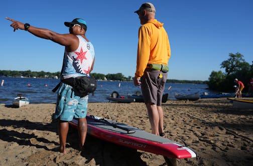 Benjie Mahigab, left, and Steve Wacholz stand on the beach as they survey the wind and waves on Lake Minnetonka ahead of the Big Island and Back Paddle Saturday, Aug. 12, 2023 in Excelsior, Minn. The event raises money for ICA Foodshelf and Freshwater.