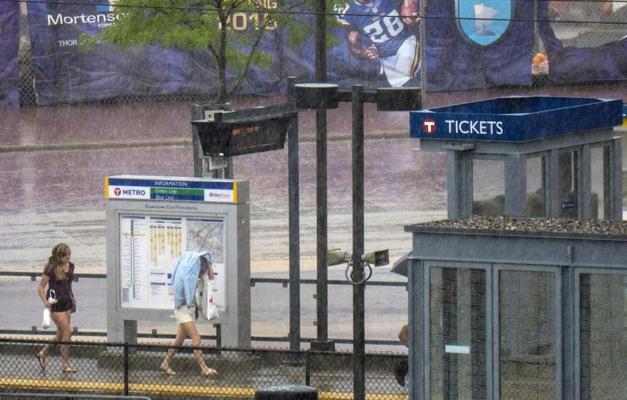 Train riders run for cover at the Vikings stadium stop when the rain started coming down in buckets Saturday afternoon.