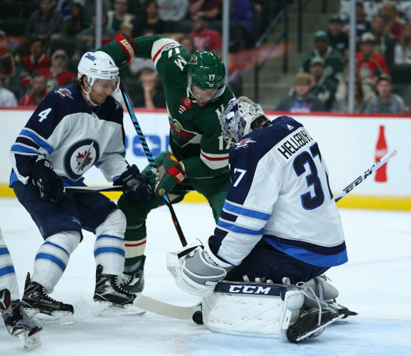 Minnesota Wild left wing Marcus Foligno (17) tries to shove the puck between the pads of Winnipeg Jets goalie Connor Hellebuyck (37) while defended by Jets' Ben Chiarot (7) during the first period of an NHL hockey preseason game Thursday, Sept. 21, 2017, in Minneapolis. (Jeff Wheeler/Star Tribune via AP)