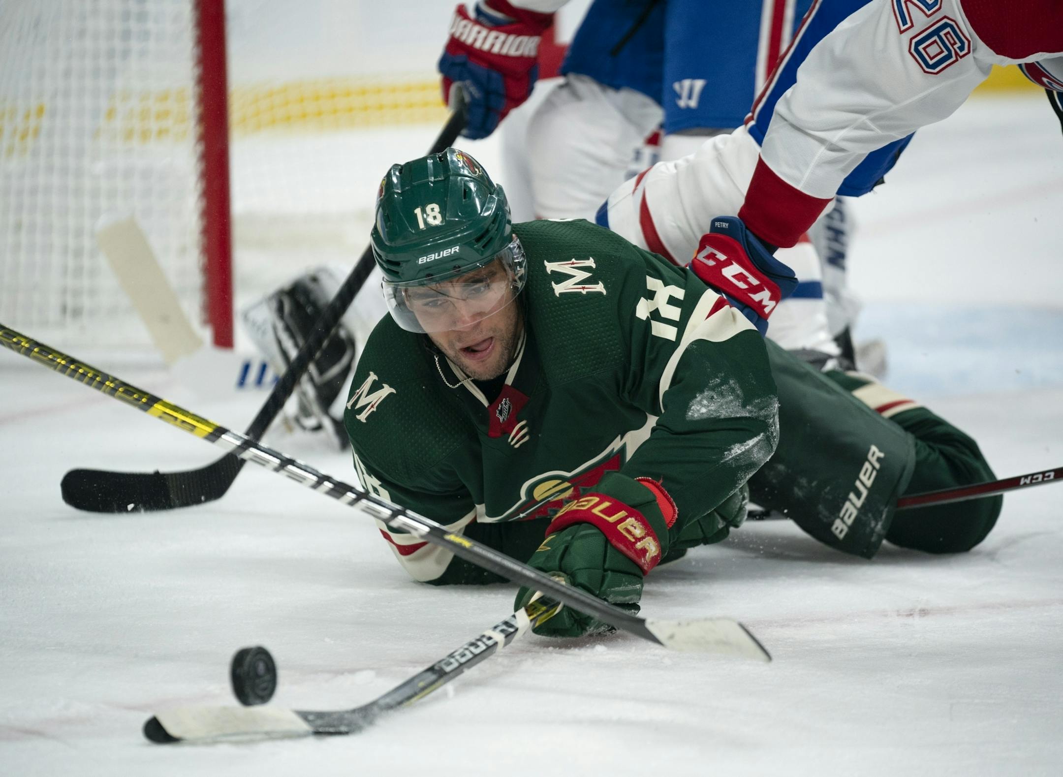 Minnesota Wild left wing Jordan Greenway (18) kept control of the puck after dropping to the ice in the first period while defended by Montreal Canadiens defenseman Jeff Petry (26).