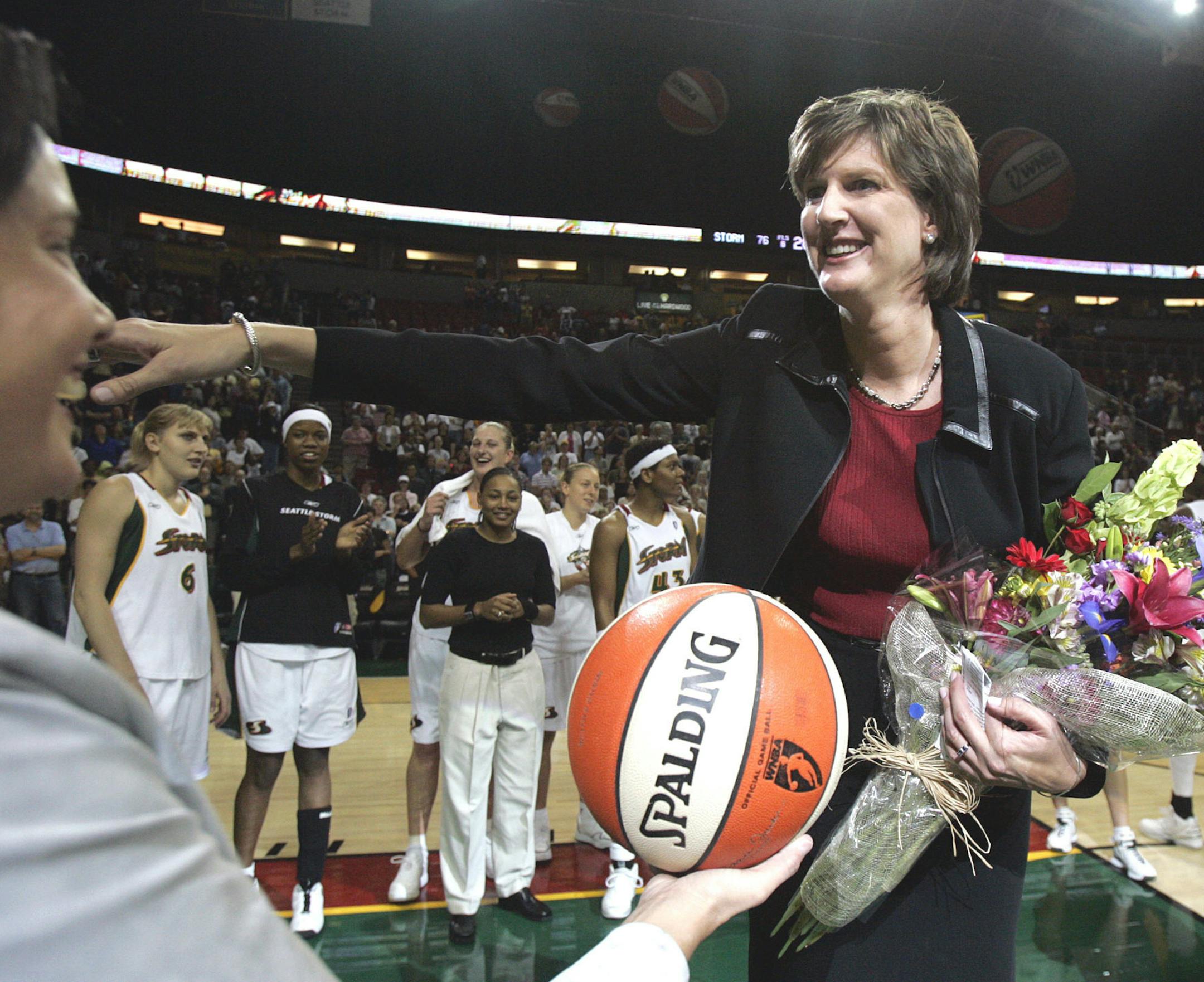 FILE - In this Aug. 19, 2005, file photo, Seattle Storm coach Anne Donovan, right, smiles as she is handed the game ball by team official Karen Bryant following the Storm's victory over the Minnesota Lyn in Seattle. The victory gave Donovan her 100th career WNBA victory as a coach, the first woman to reach that plateau. Donovan died Wednesday, June 13, 2018, of heart failure. She was 56. Donovan's family confirmed the death in a statement. (AP Photo/Elaine Thompson, File)