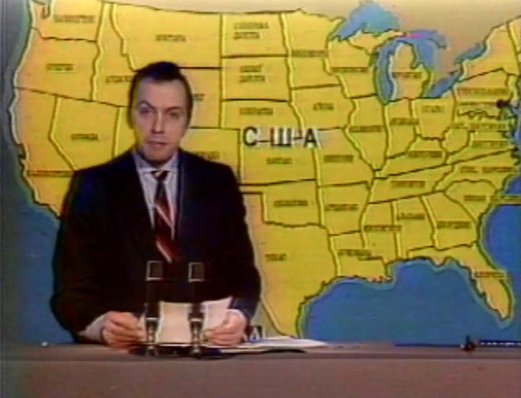 A Soviet newscaster in front of a map of the United States during an episode of 'Channel 3, Moscow.'