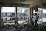 Palestinians look at the aftermath of the Israeli strike on a U.N.-run school that killed dozens of people in the Nusseirat refugee camp in the Gaza S