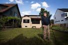 Dan Shuster stands in the backyard of his modest-sized rambler in Linden Hills, which is now dwarfed by the large new homes on either side.