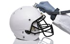 iStock
A football helmet and doctors hand holding a stethoscope on the crown of the helmet. Sports Concussion.