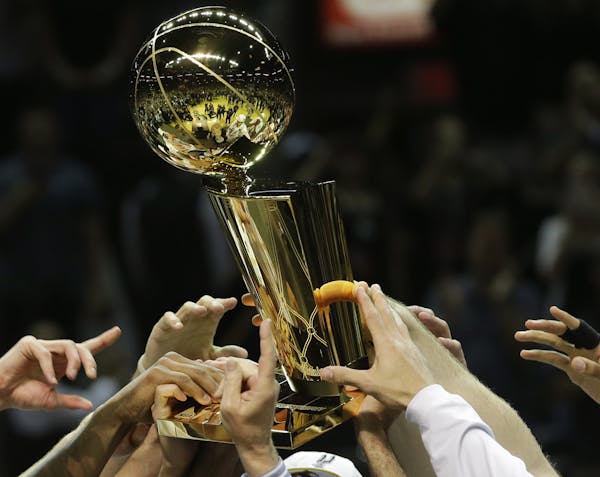 The San Antonio Spurs lift the Larry O'Brien NBA Championship Trophy after Game 5 of the NBA basketball finals on Sunday, June 15, 2014, in San Antoni