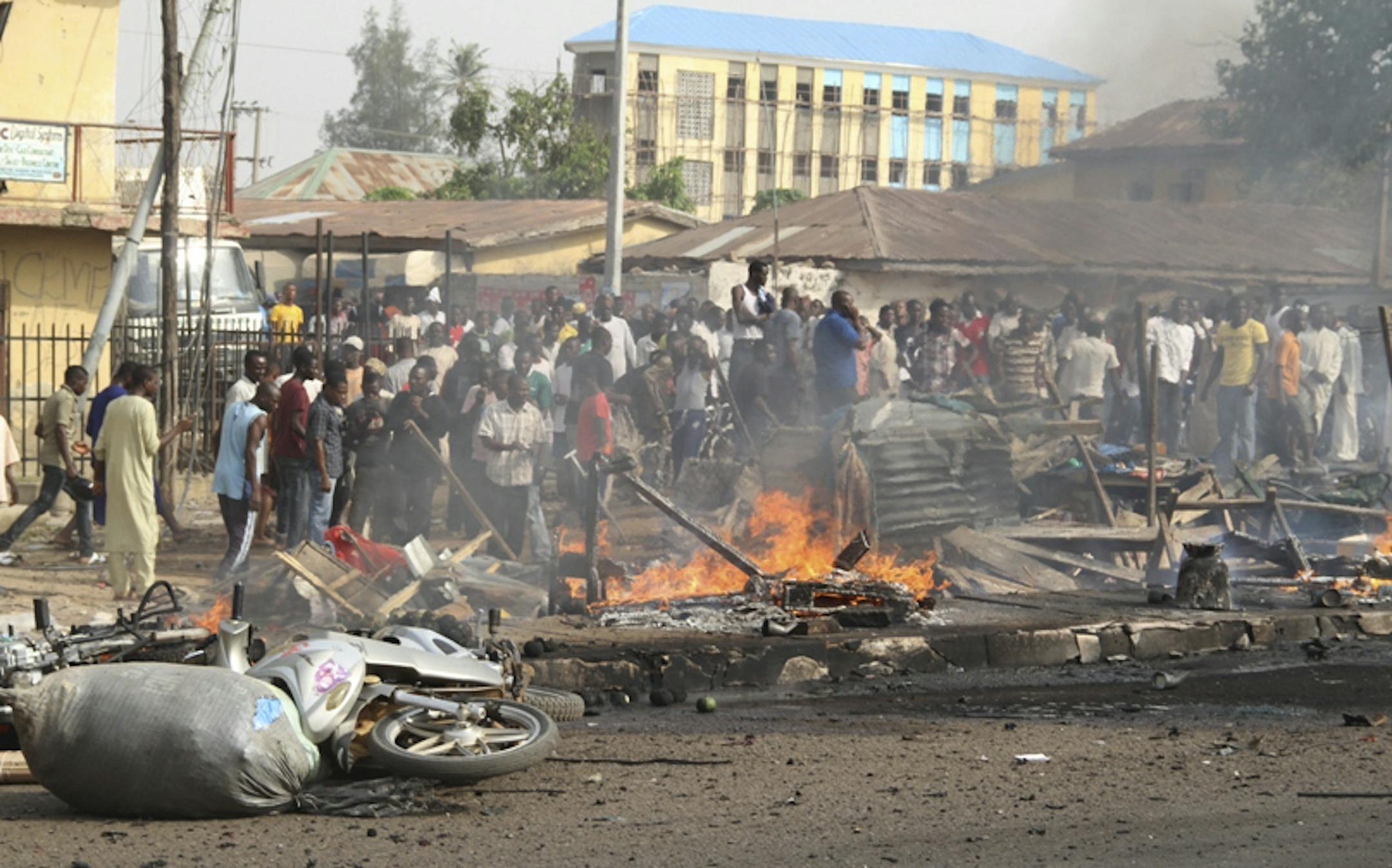 People gather at the site of a bomb explosion at a road in Kaduna, Nigeria on Sunday, April 8, 2012. An explosion Kaduna in central Nigeria that has seen hundreds killed in religious and ethnic violence in recent years, causing unknown injuries as diplomats had warned of possible terrorist attacks over the Easter holiday, police said.(AP Photos/Emma Kayode)
