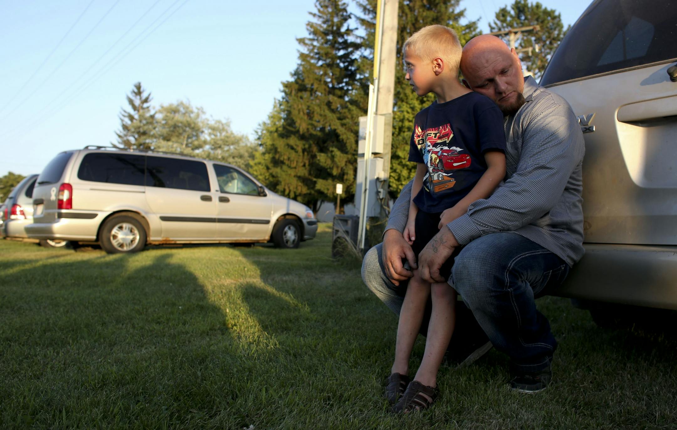 Derrick Koch held his son William, 6, , during a vigil for two year-old Isaiah Theis found dead in a locked car after he went missing in Centuria Wis., Thursday, July 19, 2013 .