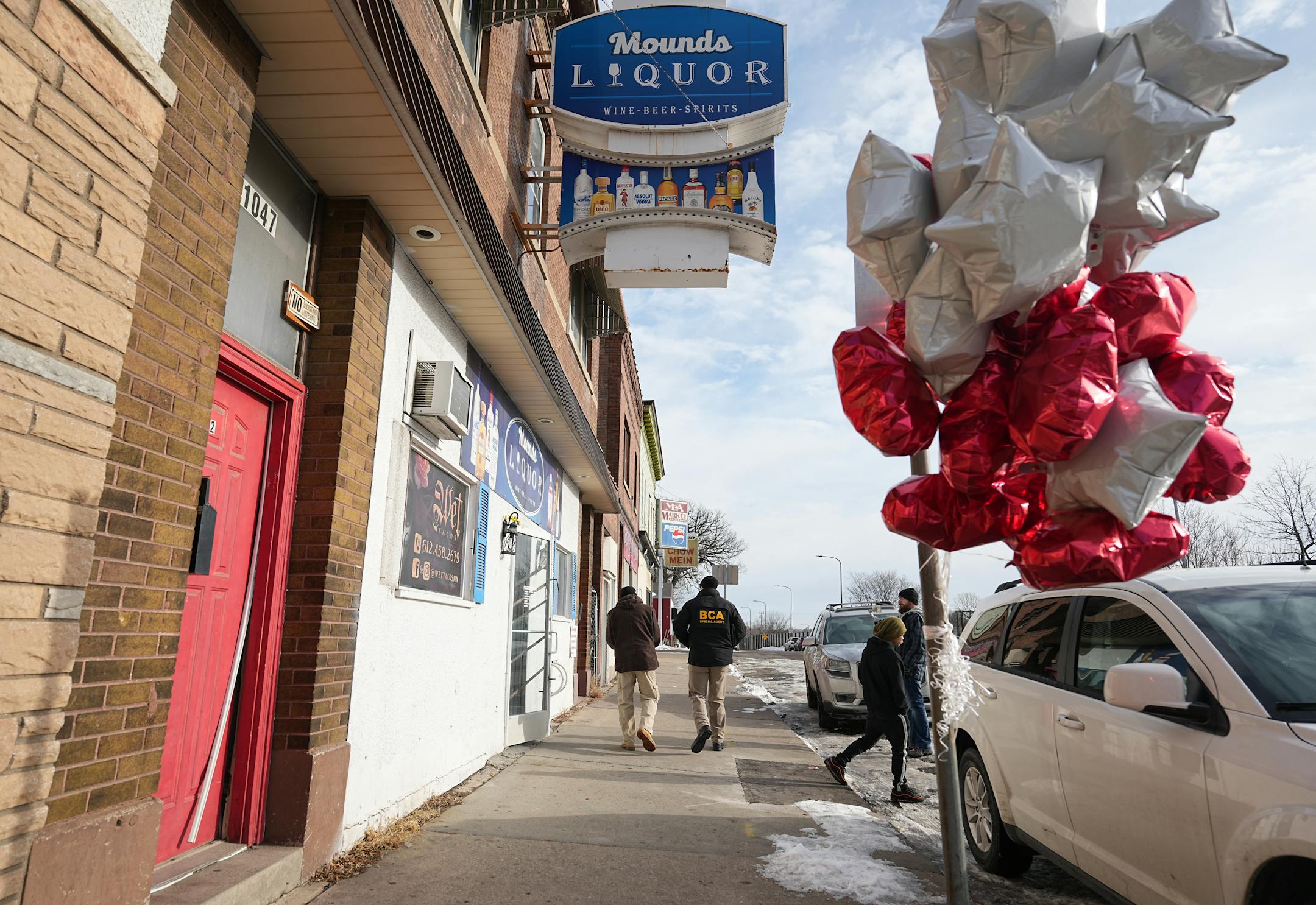 BCA investigators examine the site outside Mounds Liquor where Howard Johnson was shot on Monday evening.