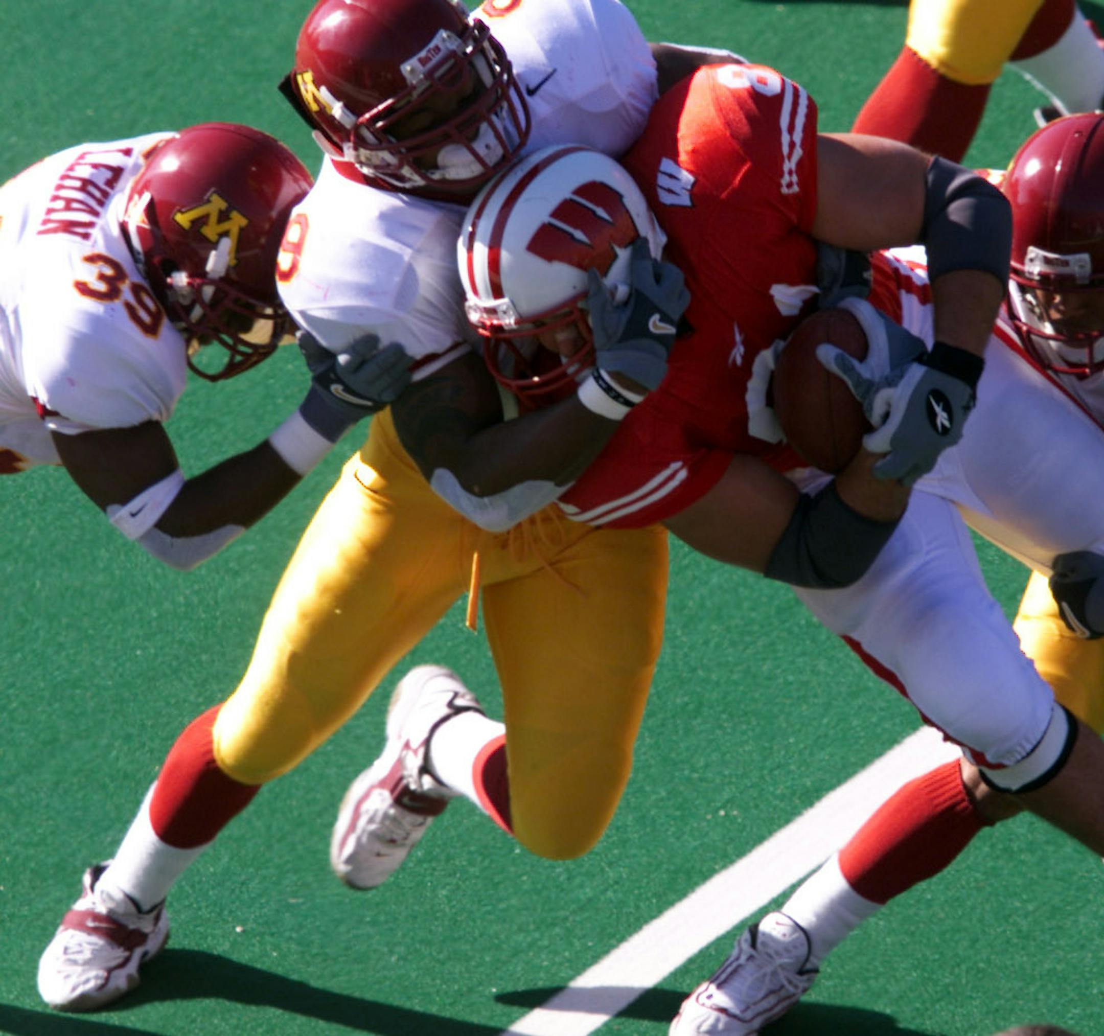 GENERAL INFORMATION: November 4, 2000--Madison, WI- Univesity of Minnesota vs. University of Wisconsin-- IN THIS PHOTO: Minnesota's Mike Lehan, #39, Curtese Poole, #9 and Clorenzo Griffin, #26, join in to tackle Wisconsin's Mark Anelli, #81, in the 1st quarter of Saturday's game. ORG XMIT: MIN2013031811093128