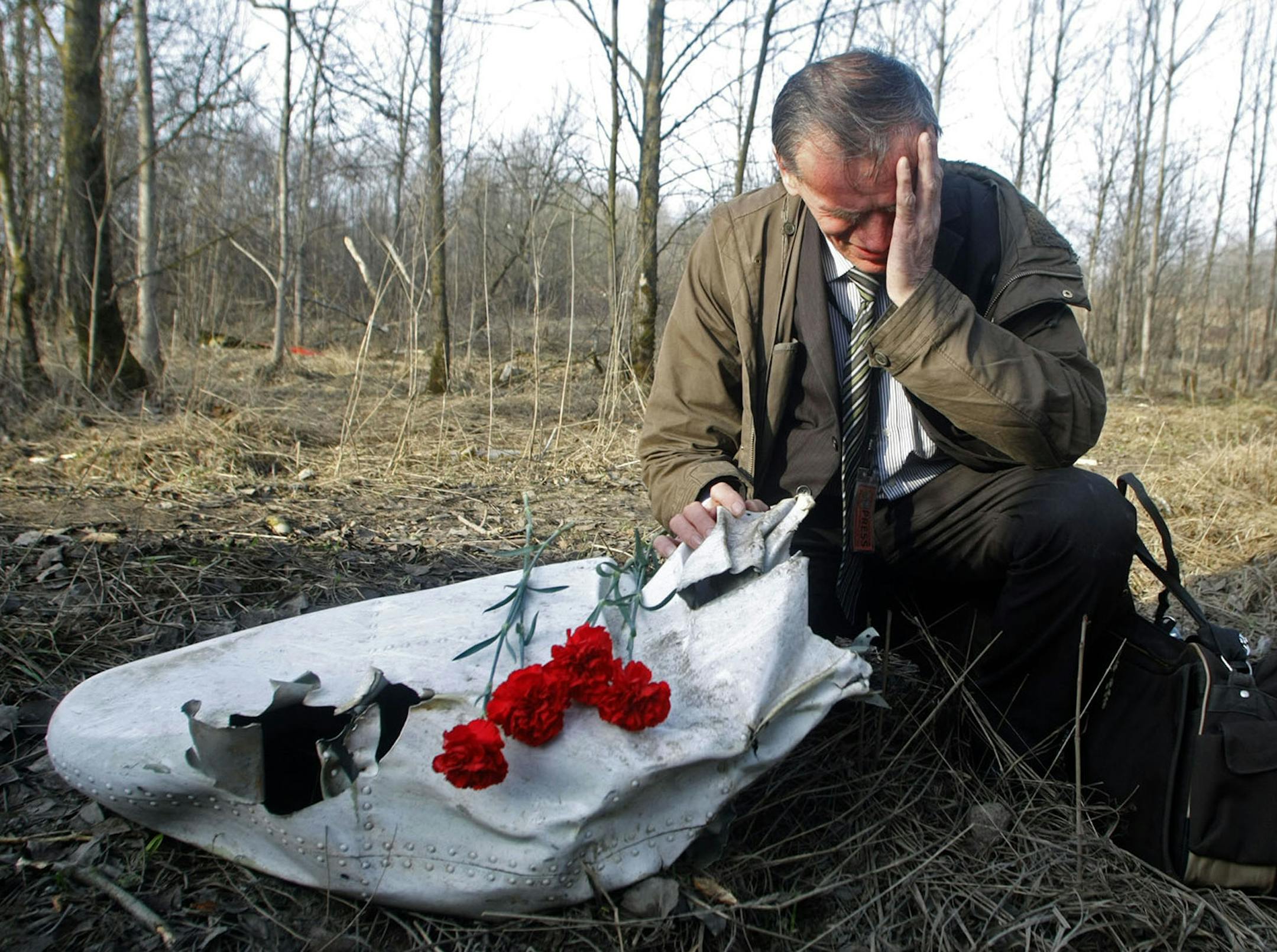 Polish Ian Grushinski grieves by a piece of the wreckage at a plane crash site near Smolensk, western Russia, Sunday, April 11, 2010. Polish President Lech Kaczynski, his wife and some of the country's most prominent military and civilian leaders died Saturday, April 10, 2010 along with dozens of others when the presidential plane crashed as it came in for a landing in thick fog near Smolensk. (AP Photo/Mikhail Metzel) ORG XMIT: MIN2013041212292134
