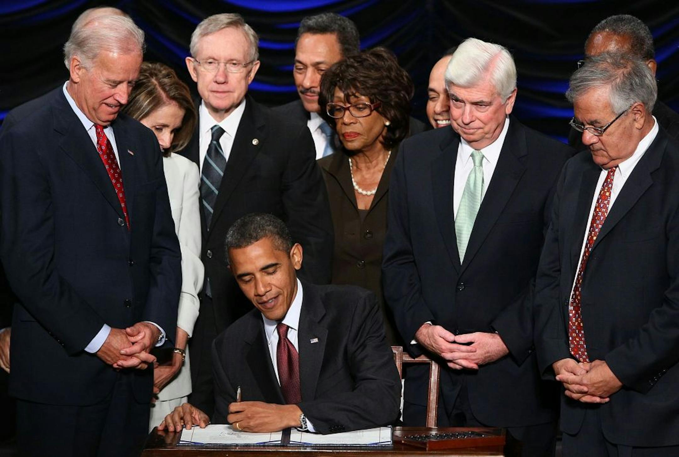 U.S. President Barack Obama signs the Dodd-Frank Wall Street Reform and Consumer Protection Act at the Ronald Reagan Building in Washington, D.C., Wednesday, July 21, 2010. Also pictured, from left, Vice President Joe Biden, Speaker of the House Nancy Pelosi (D-Calif.), Senate Majority Leader Harry Reid (D-Nev.), Rep. Maxine Waters (D-Calif.), Sen. Chris Dodd (D-Conn.) and Rep. Barney Frank (D-Mass.).