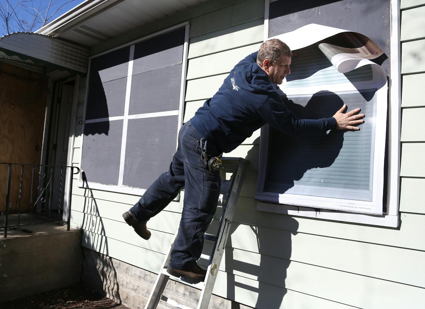 Tim Korby, of Korby's Handyman Services, installed the vinyl coverings onto the boarded up windows on this home. ] (KYNDELL HARKNESS/STAR TRIBUNE) kyndell.harkness@startribune.com At a forfeited home in Minneapolis Min., Thursday, March 31, 2014. Hennepin county installed the vinyl covering for the boarded up windows and door it has purchased from Michigan-based Home Illusions.