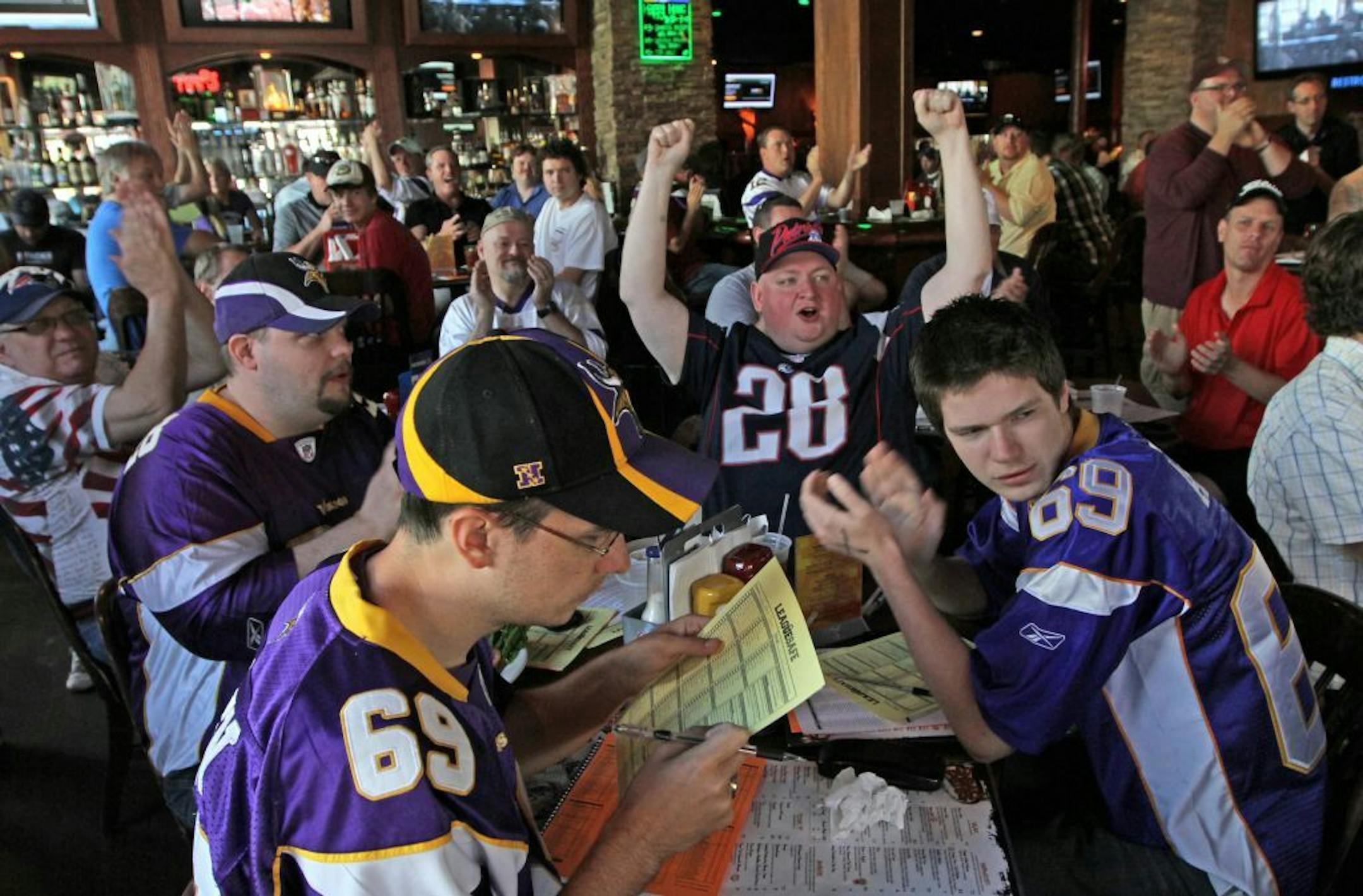 (left to right-front row-in NFL jerseys) Tom Chandler of Inver Grove Heights, Kenny Cruzen of Minneapolis, Patrick Wirkus of Inver Grove Heights and Zach Cruzen of Minneapolis attended a fantasy football camp at Sneaky Pete's in downtown Minneapolis. The bar was packed with 400 to 500 fans of fantasy football.