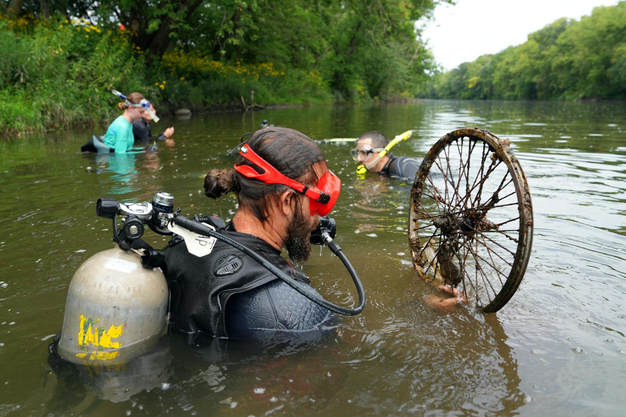 Hunter Poffinbarger, a student intern with the Minnesota DNR, looks over a wheel spoke as he and a team search for black sandshell and mucket mussels while they surveyed their population in a section of the Cedar River.