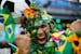 A Brazil soccer fan covered in flowers and his nation's flag cheers inside the FIFA Fan fest area before the start of the World Cup openes between Bra