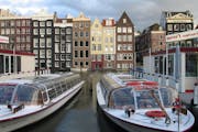 Tour boats await passengers in downtown Amsterdam. Amsterdam's canals criss-cross the old city making it easy to see it by boat. The traditional house