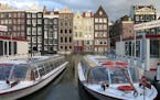 Tour boats await passengers in downtown Amsterdam. Amsterdam's canals criss-cross the old city making it easy to see it by boat. The traditional house