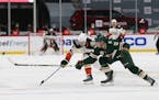 Anaheim's Ben Hutton (7) and the Wild's Nick Bonino (13) go after the puck during the second period on March 22
