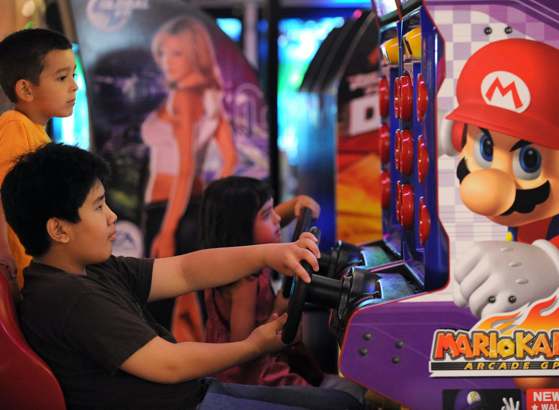 Alex Magasco, 12, played video games with his cousins Josh, 7, and Maya Moen, 5, at Brunswick Zone XL in Blaine on Tuesday. Experts say video games, cell phones and computers are turning many kids into sedentary teenagers and more exercise options are needed.