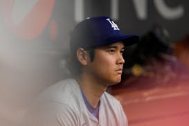 The Dodgers' Shohei Ohtani sits in the dugout during the eighth inning of Sunday's loss to the Reds in Cincinnati.