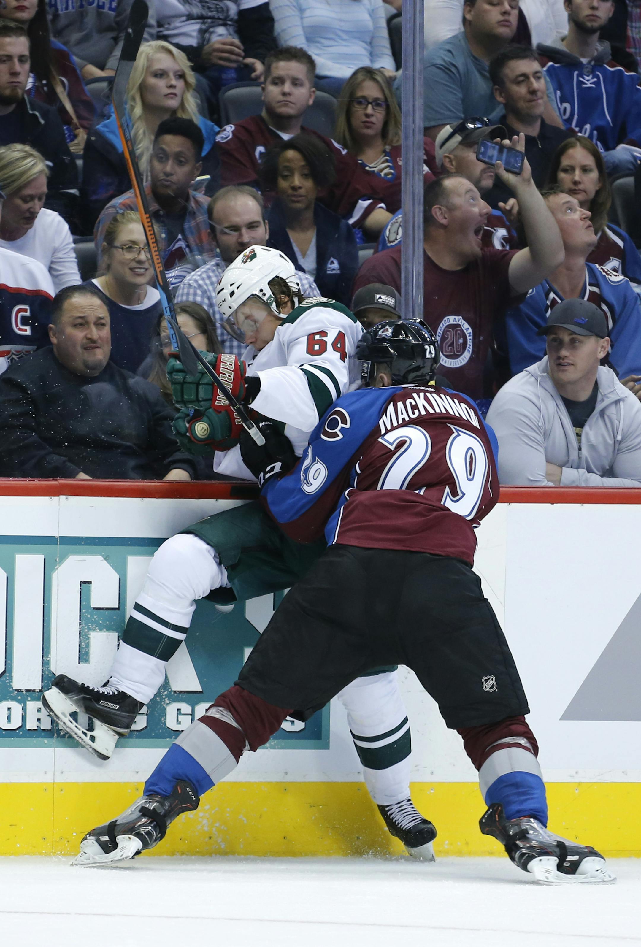 Colorado Avalanche center Nathan MacKinnon (29) checks Minnesota Wild center Mikael Granlund (64) into the boards during the second period of an NHL hockey game Thursday, Oct. 8, 2015, in Denver. (AP Photo/Jack Dempsey)