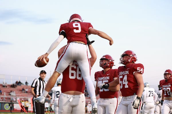Maple Grove's Jacob Kilzer (9) is lifted in the air by lineman Hunter Gerber (66). Kilzer scored 3 touchdowns in the Crimson's 43-14 win over Champlin
