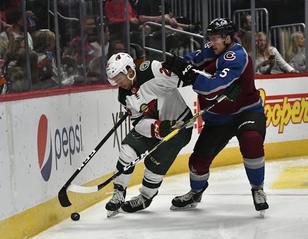 Minnesota Wild's Gerald Mayhew (26) battles for the puck along the boards with Colorado Avalanche defenseman Dan Renouf (5) during the second period i