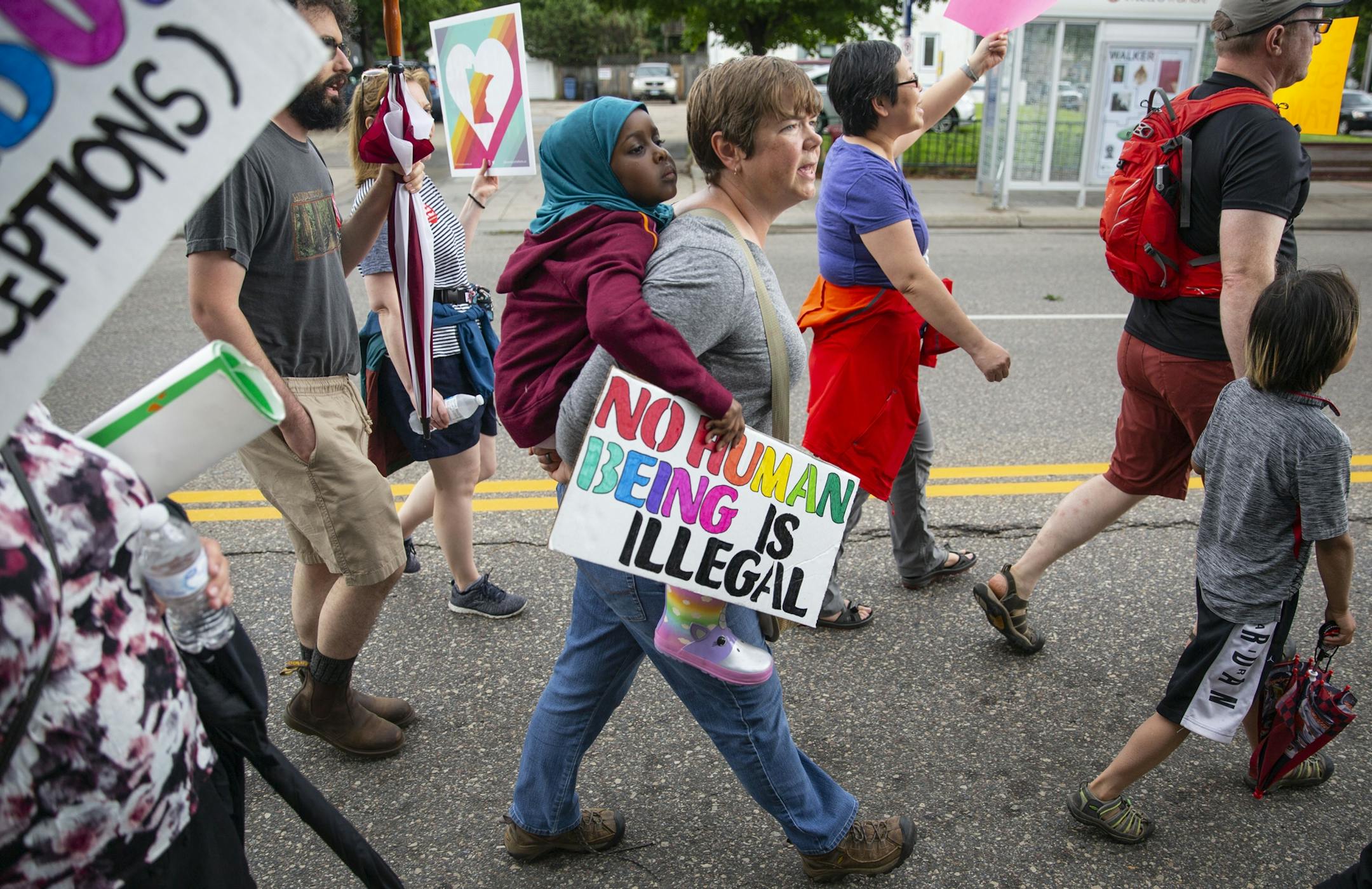 Hikmah Warsame rides on the back of her mother's friend, Anna Kam, during the march. ALEX KORMANN ¥ alex.kormann@startribune.com Approximately 1,000 people marched through the streets of Minneapolis on Sunday June 30, 2019 protesting the treatment of migrants on the U.S. border. "Stop separating families, close the camps," said Mari Mansfield, an organizer for the event.