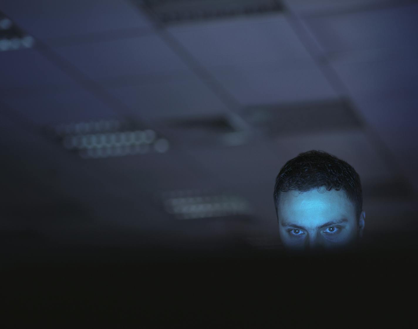 Computer hacker working on laptop late at night in office