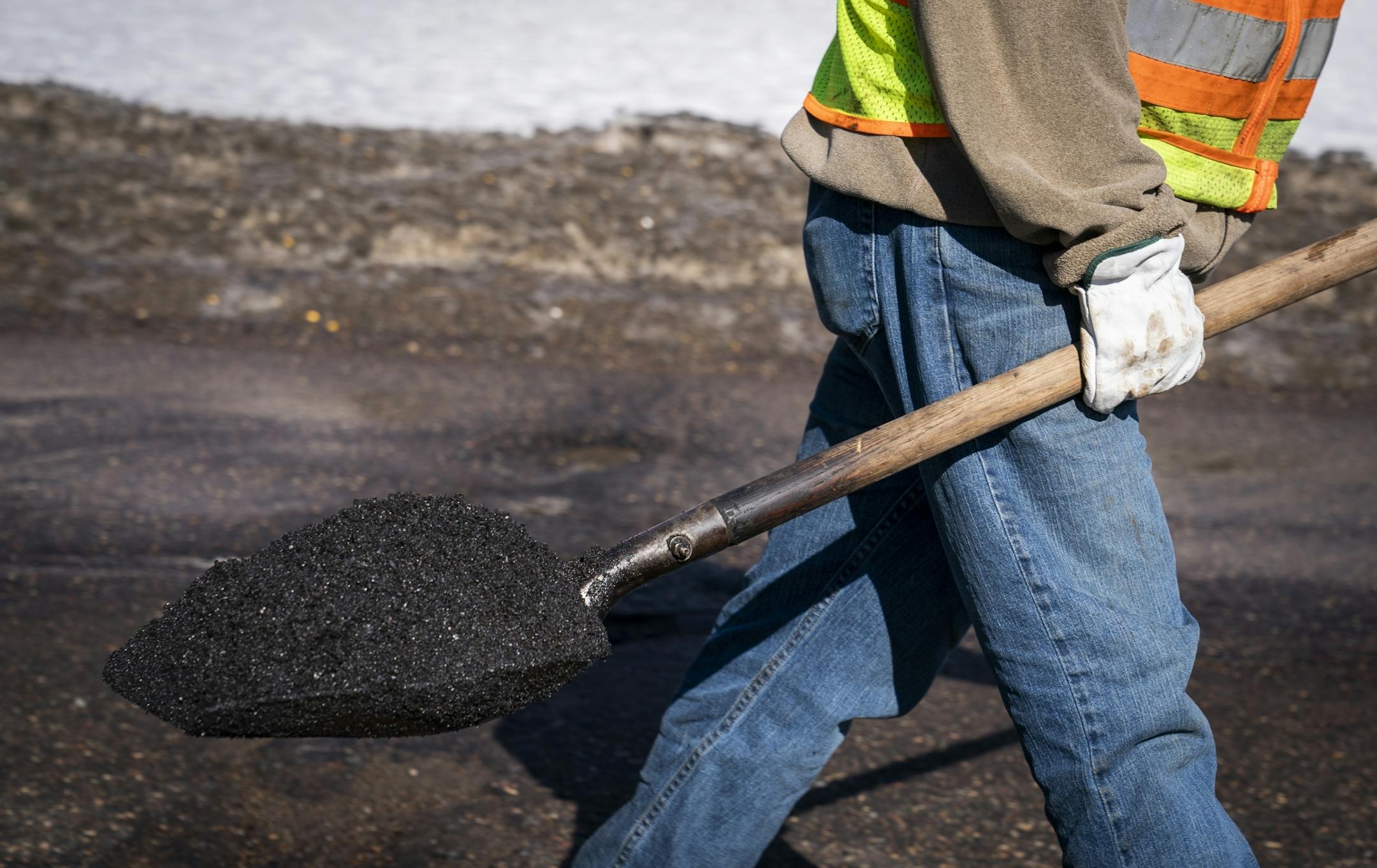 St. Paul Public Works street service worker Bradley Therres caries fresh asphalt to fill a pothole.